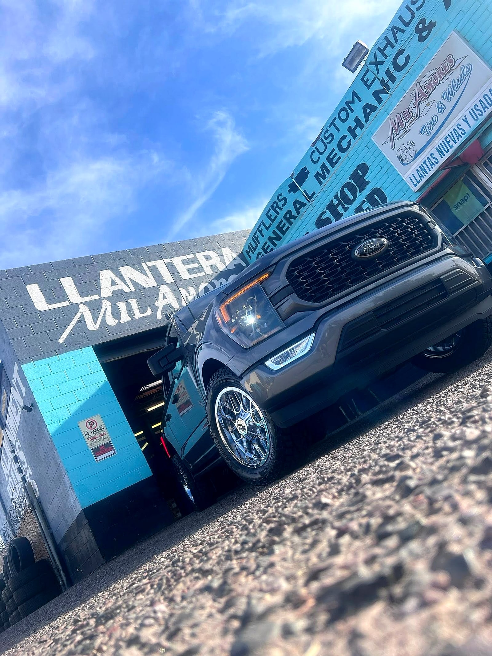 Gray Ford F-150 on new wheels under the Llantera Mil Amores wall
