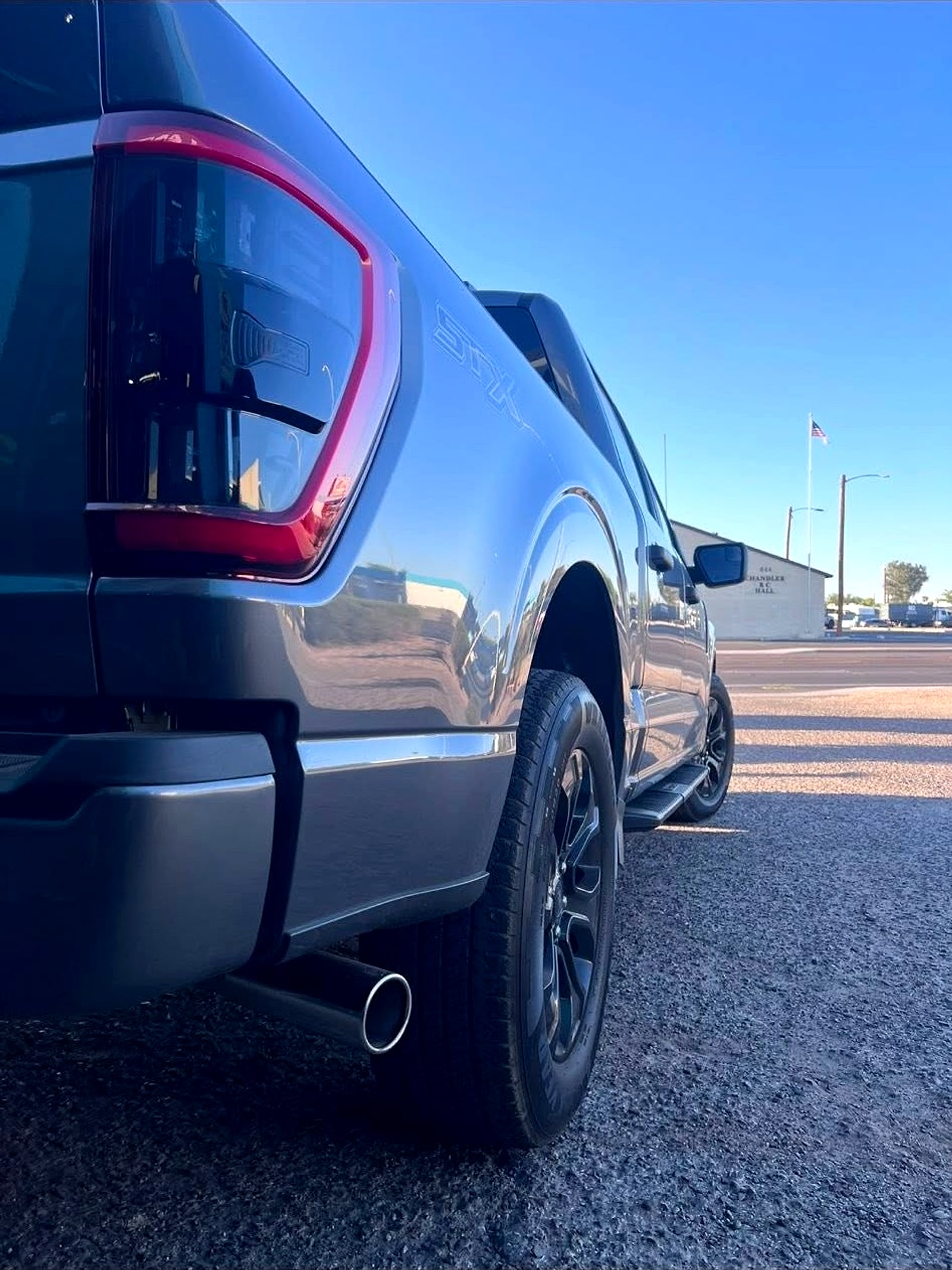Exhaust tip under the rear of a gray pickup