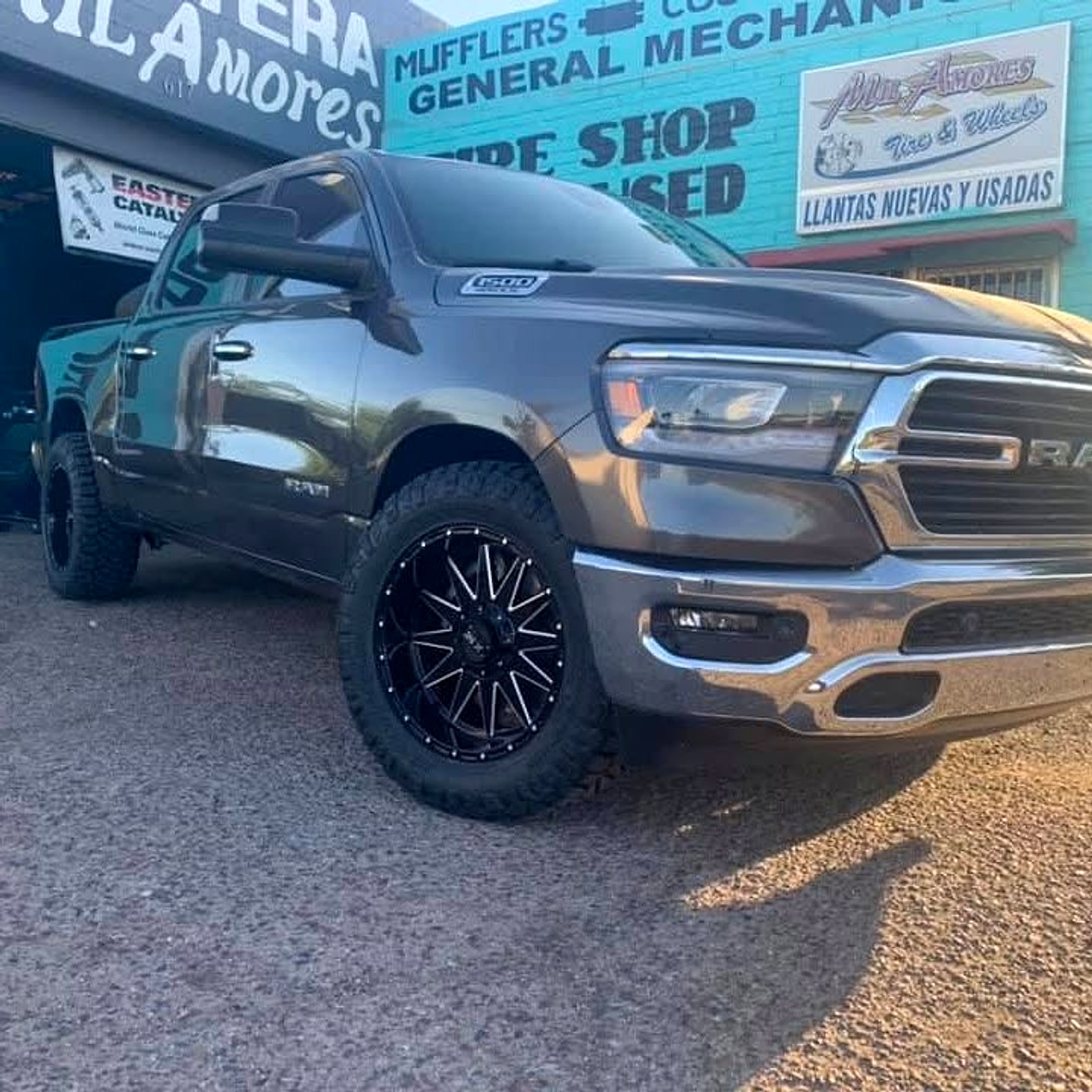 Ram 1500 on black custom wheels in front of the shop