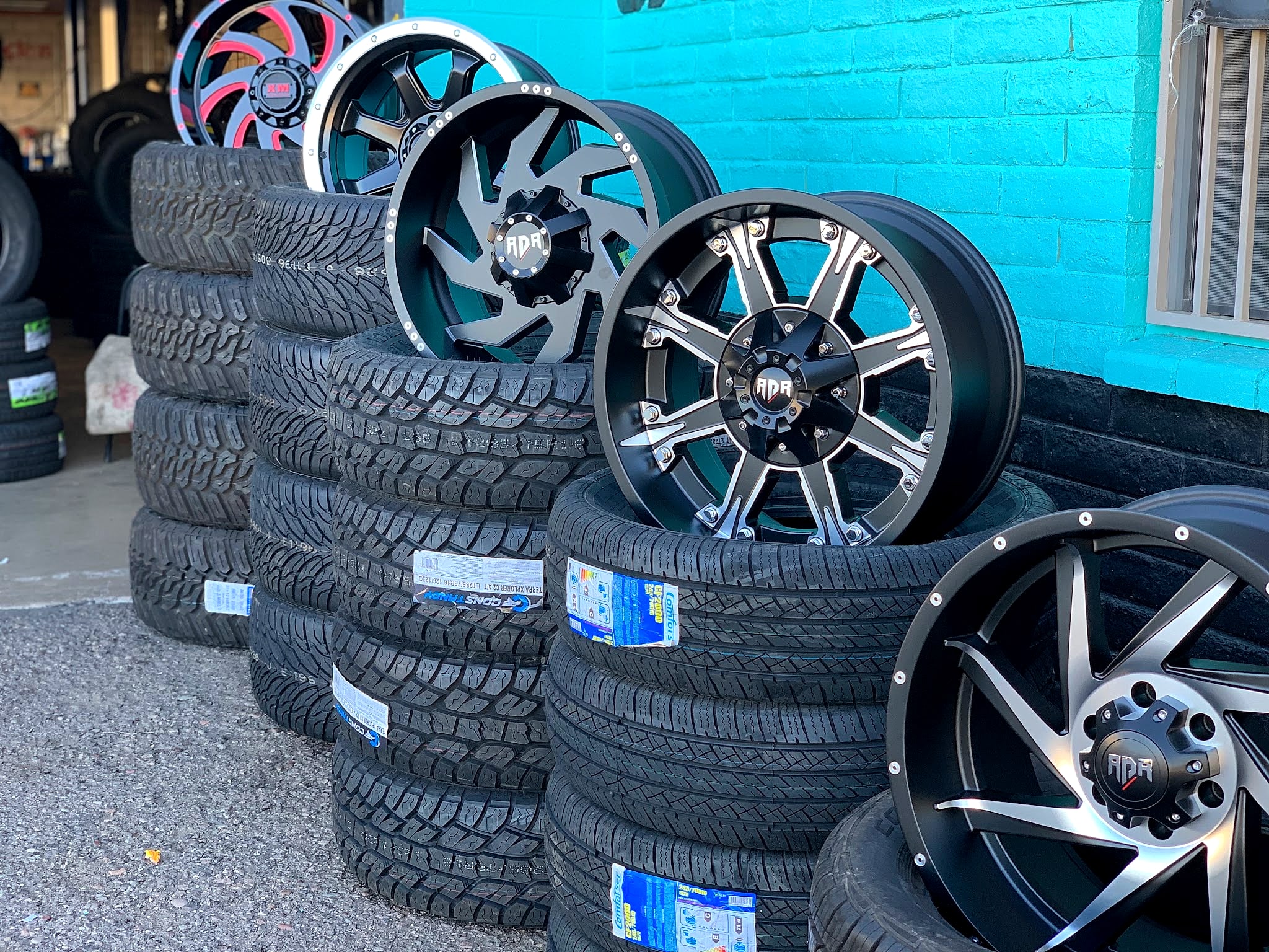 Stacks of tires and custom wheels against the turquoise wall