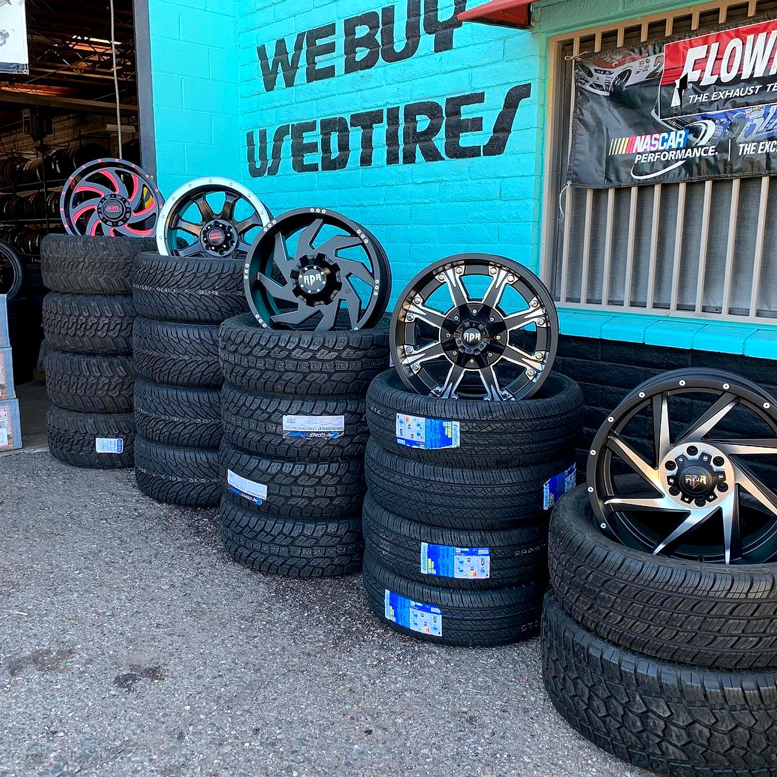 Custom wheels and tire stacks by the We Buy Used Tires wall