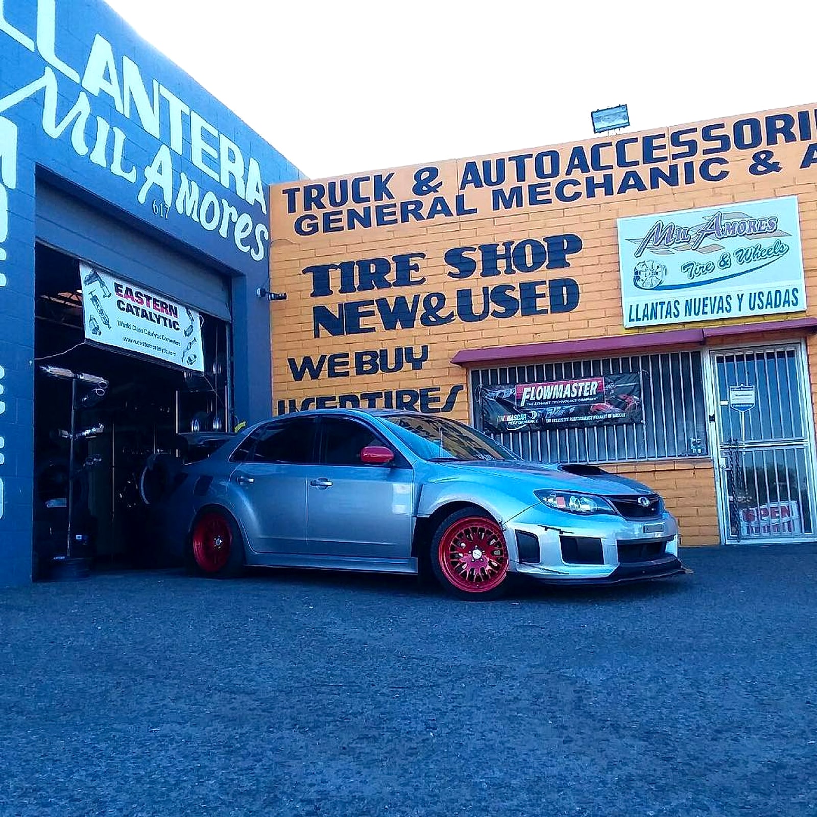Silver Subaru with red wheels in front of the shop